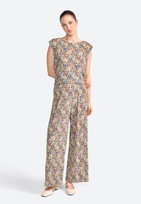 Top multicolore senza maniche e pantaloni a gamba larga in tessuto leggero e stampato, con vestibilità comoda e vita elastica, completati da scarpe basse.