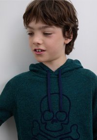 Grön hoodie i texturerat tyg med en stor marinblå dödsskalle på framsidan och matchande dragsnören i luvan.