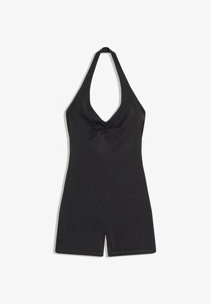 Salopetă neagră cu gât halter, decolteu adânc în V și picioare scurte, material neted și detaliu ușor strâns în centrul bustului.