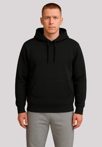 Black hoodie with a kangaroo pocket, adjustable drawstring hood, and ribbed cuffs, paired with light gray sweatpants. Smooth, solid texture.