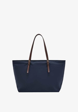 Grand sac cabas bleu marine avec deux longues bretelles ajustables en cuir marron sur fond blanc.