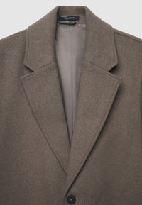 Brauner Wollmantel mit breiten, abgeschrägten Revers und einem einzelnen schwarzen Knopf, der eine glatte, hellgraue Innenfutter im Kragen zeigt.