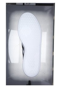 Svart sko med vit sula, med en strukturerad, diamantmönster. Adidas-logotypen är synlig på den nedre sulan i mitten.