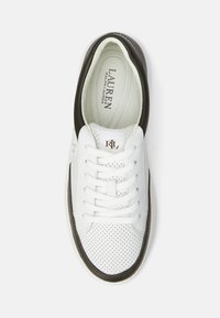 Baltas ādas sneakeris ar melniem akcentiem, perforēts dizains, apaļš purngals un kaklasaites. Iekšpusei ir gaiša odere ar logotipa detaļu.
