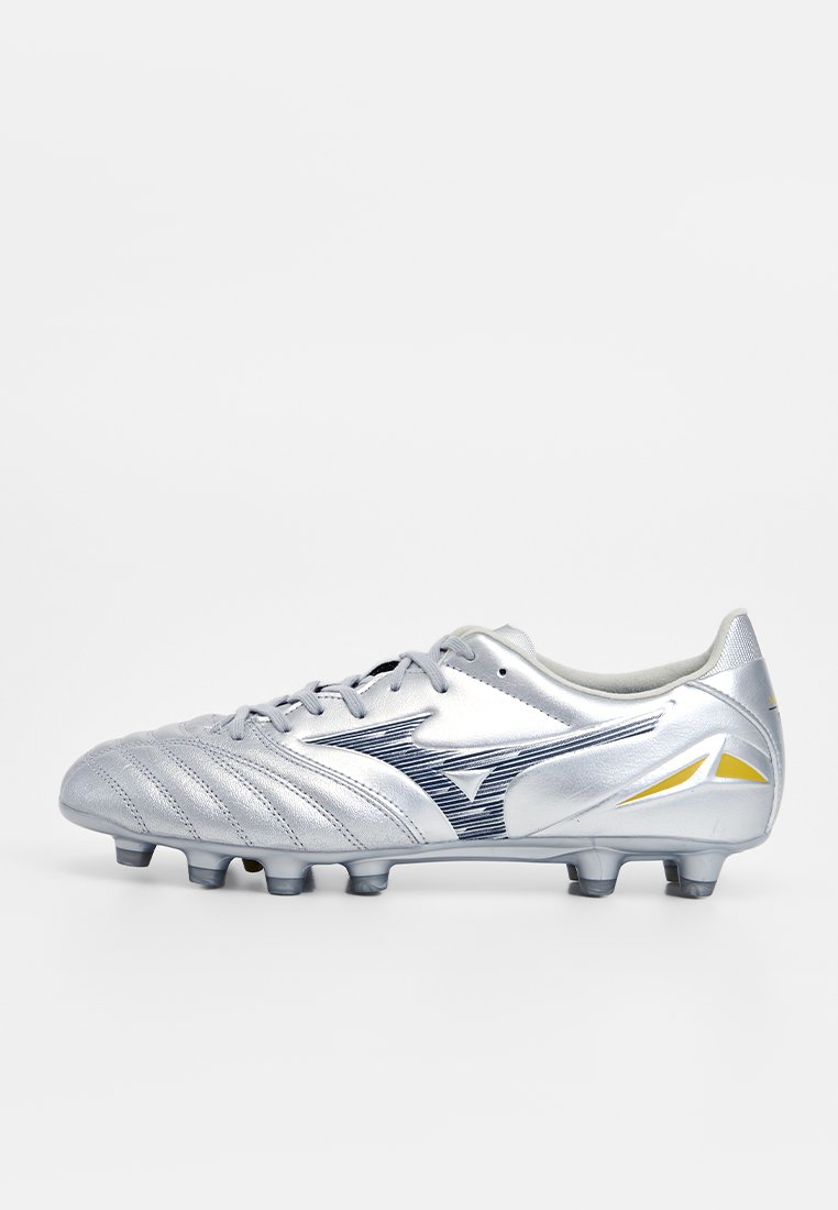 Coque de football argentée avec un matériau synthétique texturé, présentant des rayures horizontales, un accent de logo et un détail jaune sur le talon.