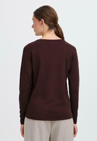 Bordo, pulover s dugim rukavima i okruglim izrezom, napravljen od mekog materijala s rebrastim detaljima na rubovima i manžetama, glatke teksture.