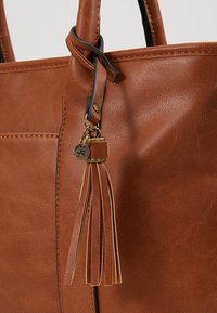 Brun håndtaske i syntetisk læder med slankt design, syninger og en guldfarvet hardwarekvast som pynt.
