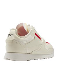 Baskets en cuir crème avec des accents rouges, conception à lacets, col rembourré et semelle en caoutchouc texturé. Présente un logo sur le talon et sur le côté.