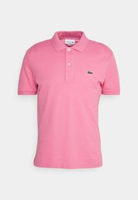 Polo rose en coton avec col, patte de boutonnage à deux boutons, et logo crocodile vert brodé sur la poitrine gauche. Manches courtes.