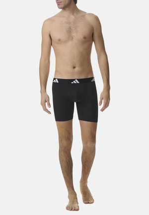 Schwarze Boxer-Briefs mit einem weißen Logobund, körpernahe Passform, aus glattem Stoff, Oberschenkellänge und minimalen Nahtdetails.