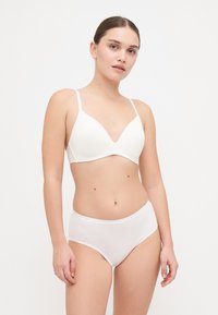 White seamless bra with lightly padded, V-shaped cups and adjustable straps, paired with matching high-waisted white briefs. Smooth texture.