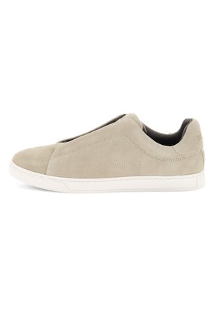 Beige suède instapsneaker met witte zool, lage enkellengte en subtiele stikdetails op de zijkanten.