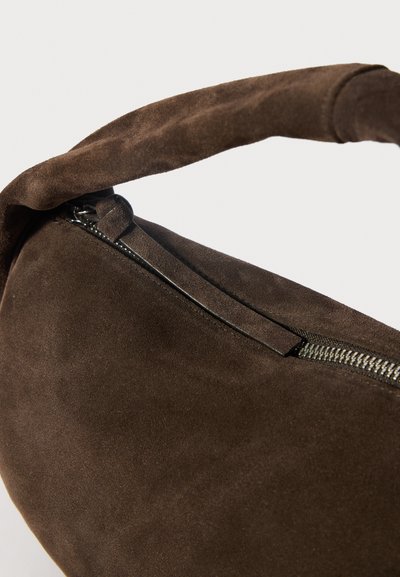 Καφέ σουέτ τσάντα με καμπύλο σχήμα και μαλακή υφή. Διαθέτει κλείσιμο με φερμουάρ και παχύ, διπλωμένο λουρί για μεταφορά.