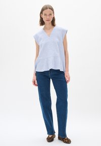 Svetlomodrý a biely pruhovaný top s krátkym rukávom a výstrihom do V, s vrstveným efektom, spárovaný s modrými džínsy a leopardími balerínkami.