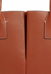 Sac en cuir marron avec une finition texturée, des poignées doubles et des coutures le long des bords et des coutures.