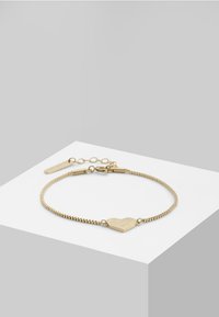 Bracelet en or avec un pendentif en forme de cœur texturé, présentant une délicate chaîne, un fermoir ajustable et un design minimaliste épuré.