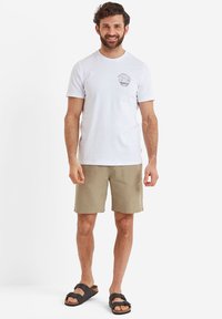 White cotton t-shirt with a round neckline and chest print, paired with tan shorts and black sandals featuring a buckle strap.