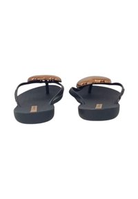 Infradito neri con una soletta testurizzata e sottili cinturini, dotati di un accento in rame lucido al centro. Design con suola piatta.