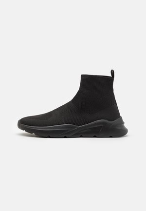 Black ankle-high sneaker with a textured knit body and elastic cuff. Features a smooth, padded sole for comfort and grip.