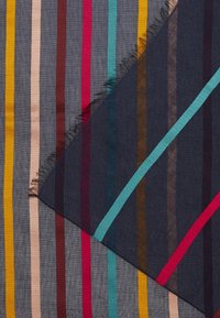 Gros plan de deux tissus rayés superposés, l'un foncé avec des rayures colorées vives, l'autre gris clair avec des rayures multicolores étroites.