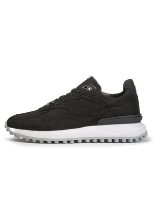 Zapatilla negra de ante y malla con suela de goma gris, que presenta superficies suaves y acentos texturizados, diseño de cordones y detalles de marca.