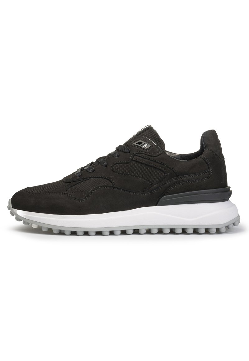 Zapatilla negra de ante y malla con suela de goma gris, que presenta superficies suaves y acentos texturizados, diseño de cordones y detalles de marca.