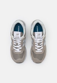 Baskets en daim et mesh couleur camel avec des lacets blancs, arborant un logo "N" gris et un amorti. Bout arrondi et semelle en caoutchouc. Design classique, modèle 574.