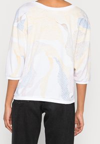 Biały sweter o luźnym kroju, z abstrakcyjnymi pastelowymi wzorami i rękawami ¾. Miękka mieszanka bawełny z prążkowanymi mankietami i dołem.