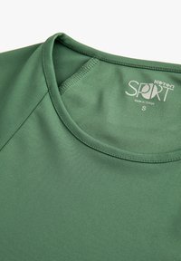 Camiseta deportiva de tejido verde oscuro sólido, con cuello redondo, textura suave y etiqueta serigrafiada que indica la talla S.