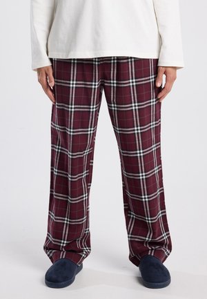 Bordeaux geruite pyjamabroek met witte en zwarte accenten, gemaakt van zachte stof, met een relaxte pasvorm en rechte pijpen. Gecombineerd met marineblauwe slippers.