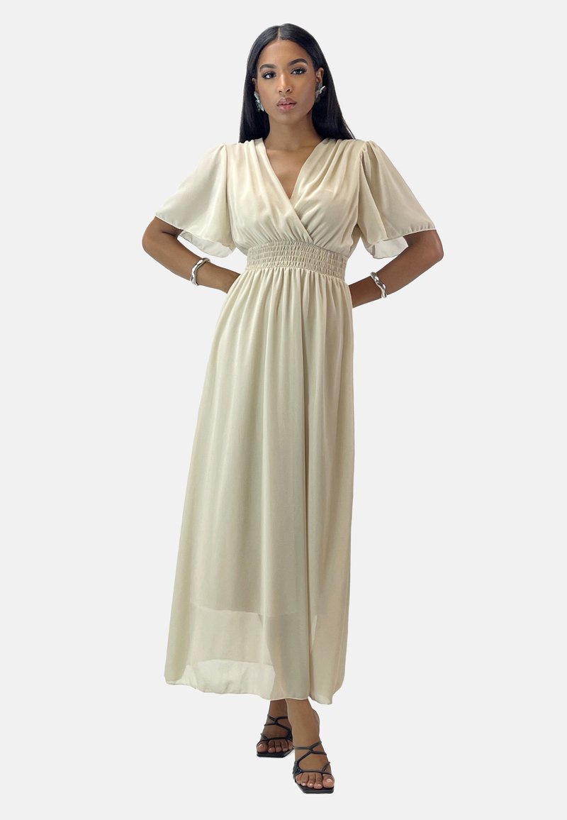 Robe longue beige en tissu léger, avec un col en V, des manches courtes bouffantes et une taille smockée pour épouser la silhouette.