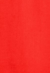 Surface texturée rouge vif solide avec des variations subtiles de teinte et de petites taches plus foncées dispersées.