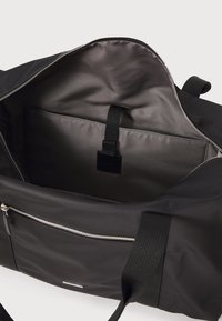 Zwarte sporttas met een gladde buitenkant, ruime binnenkant, ritssluiting en voorvak met zilverkleurige accessoires en band.