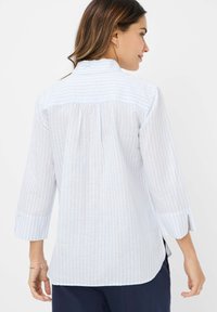 Light blue and white striped shirt with a high collar, three-quarter sleeves, and a pleated back, made from a soft, textured fabric.