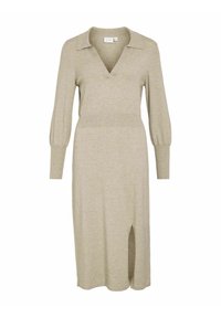 Beige gebreide jurk met een v-hals, lange pofmouwen en een split aan de zijkant. Beschikt over een kraag en een gladde textuur. Middenlange uitvoering.