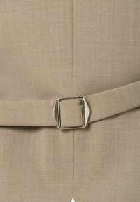 Beige stof met een gladde textuur bevat een rechthoekig zilveren gespdetail op een riem. Het materiaal heeft een subtiel, geweven patroon.