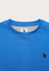 Kék pamut crewneck póló, melírozott szürke belső gallérral, bal mellen egy kis sötétkék logóval és textúrált anyaggal.
