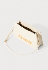 Kreemivärvi kunstnahast käekott, millel on kuldne "LOVE MOSCHINO" logo, lukuga sisemus, trapezoidne kuju ja reguleeritav õlarihm.