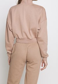 Ljust beige, kort sweatshirt med hög krage, avslappnad passform och ribbade muddarna. Slät textur, tillsammans med matchande tapered sweatpants.