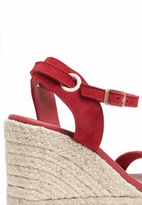 Red suede wedge sandal with a jute-wrapped heel, featuring a thin strap and buckle detail for adjustable fit, smooth inner lining.