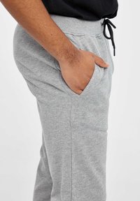 Pantalones de chándal grises de tela de jersey, con una cinturilla elástica con cordón, bolsillos laterales y un corte relajado.