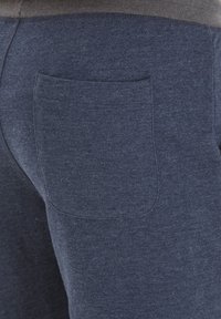Navyblå sweatpants gjorda av mjukt tyg med en enda bakficka och en kontrasterande grå elastisk midja.
