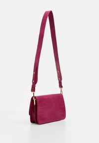 Fuchsia crossbody bag with a crocodile print texture, gold hardware accents, and an adjustable strap, featuring a rectangular shape.