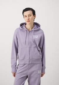 Lila zip-up kapuca narejena iz mehkega materiala, ki ima sprednji žep in kapuco z vrvico, z v刺utim logotipom EA7 na prsih.