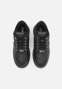 Sneaker nere in pelle con una fodera in fleece nera testurizzata, dettagli dorati, punta perforata e logo sul lato.