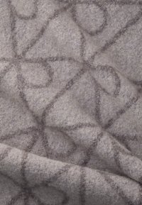 Tissu tissé gris avec une texture douce, présentant un motif de lignes grises plus foncées se chevauchant pour créer des formes abstraites.