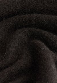 Donkerbruin textiel met een zachte, pluizige structuur, met een glad, gerimpeld oppervlak en fijne vezels. Het materiaal oogt warm en gezellig.