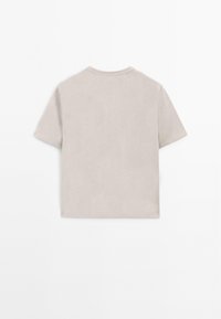 Kortærmet, lys beige T-shirt lavet af blødt bomuld. Har en rund halsudskæring og en lige kant uden yderligere designfunktioner.