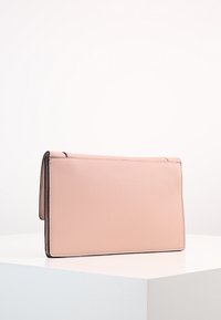 Rektangulär, ljusrosa läderväska med en texturerad yta och tunna svarta kanter längs sidorna. Ingen synlig hårdvara eller dekorationer.