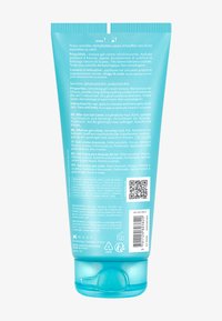 Gel-crème turquoise dans un tube souple avec un bouchon à clapet, informations détaillées sur le produit en plusieurs langues au dos, et un code QR.